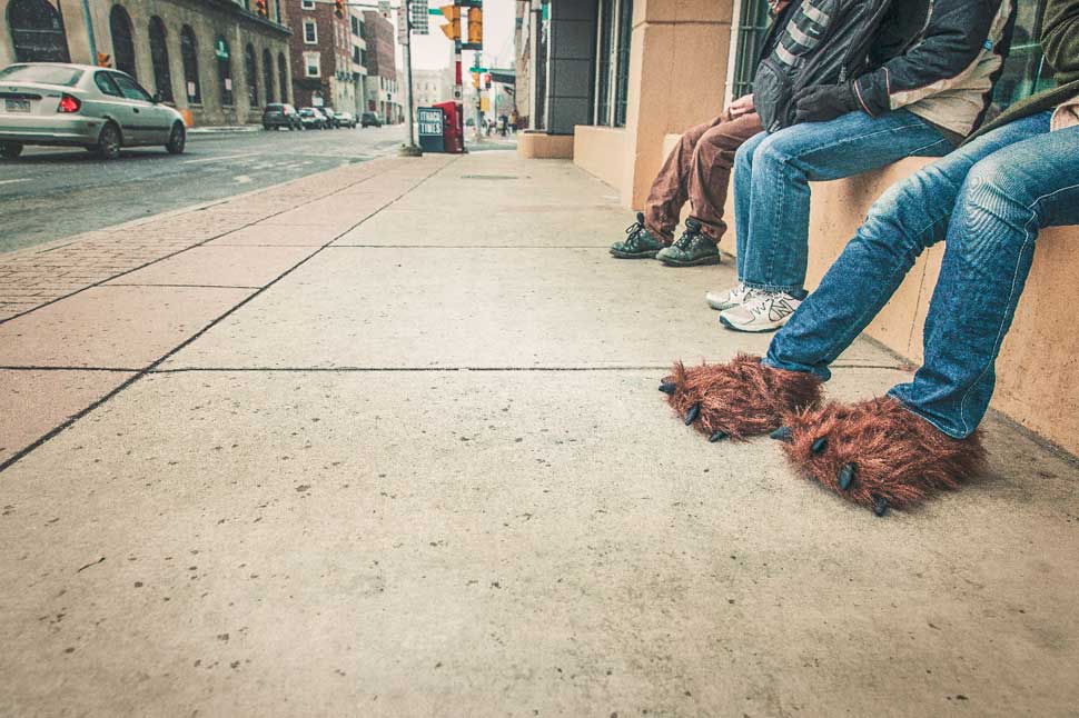 people siting in a row, one has fluffy brown monster feet