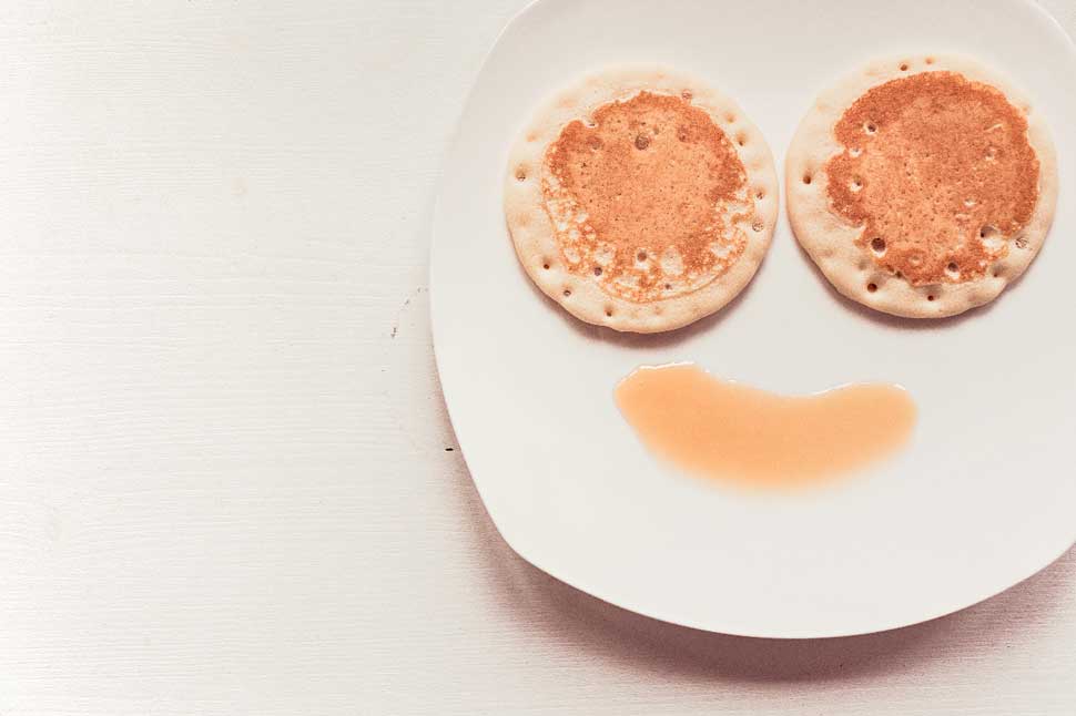 pancakes and syrup on plate making a smiley face